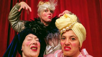 Three eccentric women take a selfie wearing makeup and brightly coloured outfits