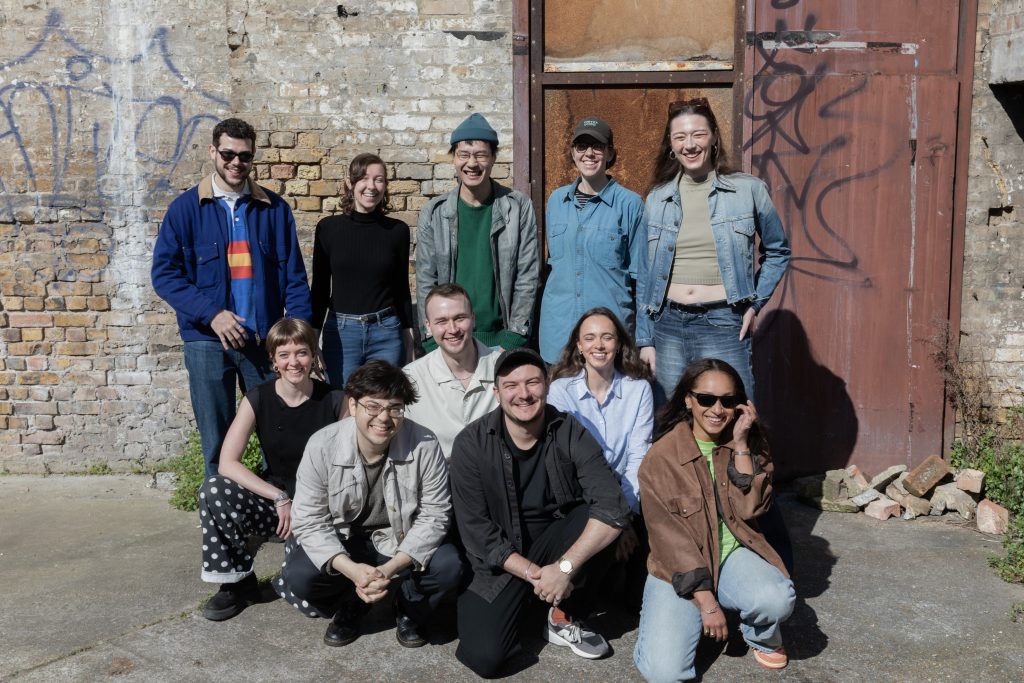 A group of artists and producers standing outside in the sunshine posing for a group photo